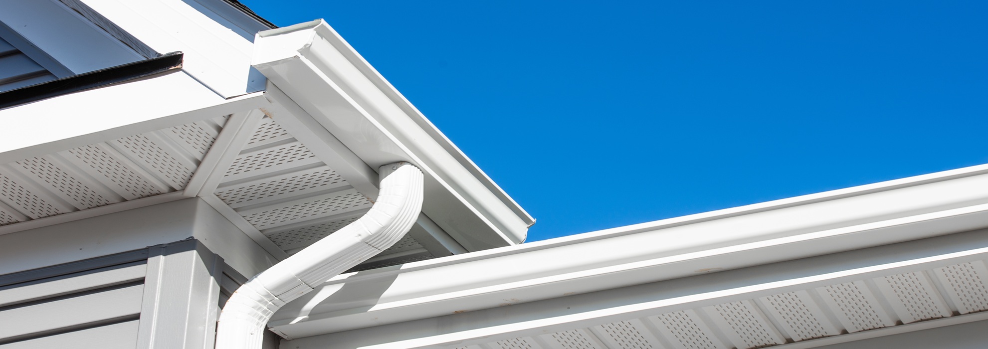 Colonial White Gutter Guard System, Soffit Providing Ventilation To The Attic, With Gray Vinyl Horizontal Siding At A Luxury American Single Family Home Neighborhood Usa