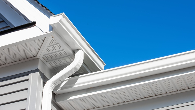Colonial White Gutter Guard System, Soffit Providing Ventilation To The Attic, With Gray Vinyl Horizontal Siding At A Luxury American Single Family Home Neighborhood Usa