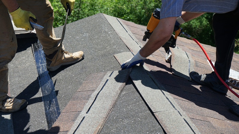 Roofer Builders Installing Asphalt Shingles Or Bitumen Tiles On A Roof Of A New House.