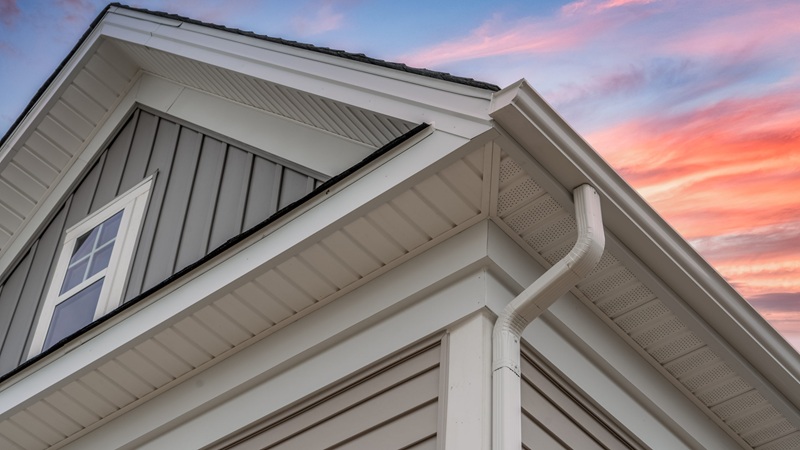 White Frame Gutter Guard System, With Gray Horizontal And Vertical Vinyl Siding Fascia, Drip Edge, Soffit, On A Pitched Roof Attic At A Luxury American Single Family Home Dramatic Sunset Sky White Frame Gutter Guard System, With Gray Horizontal And Vertical Vinyl Siding Fascia, Drip Edge, Soffit, On A Pitched Roof Attic At A Luxury American Single Family Home Dramatic Sunset Sky