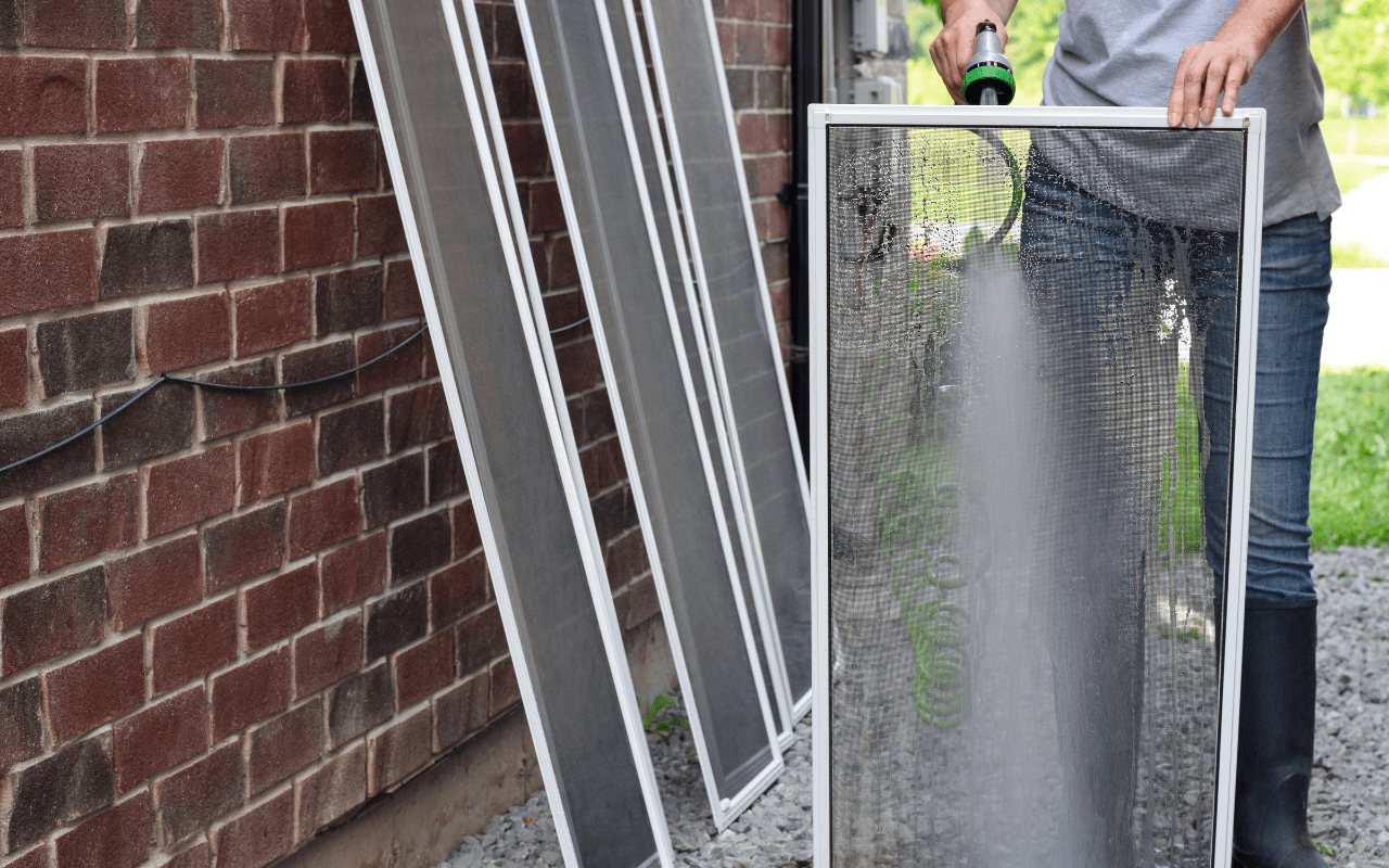 person cleaning washing window screens