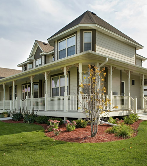 Large cream colored house with a wrap-around porch