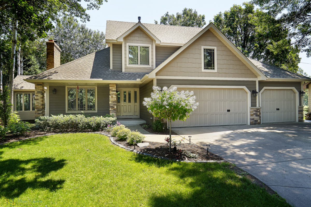 Beige and gray home with natural brick colors for accents. Clean garden wraps around front walkway.