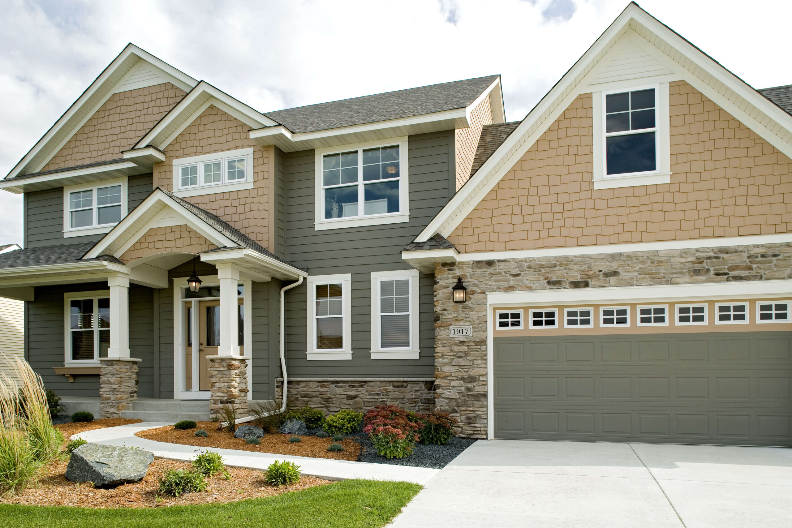 two toned house with beige and gray vinyl siding mixed with manufactured stone siding.