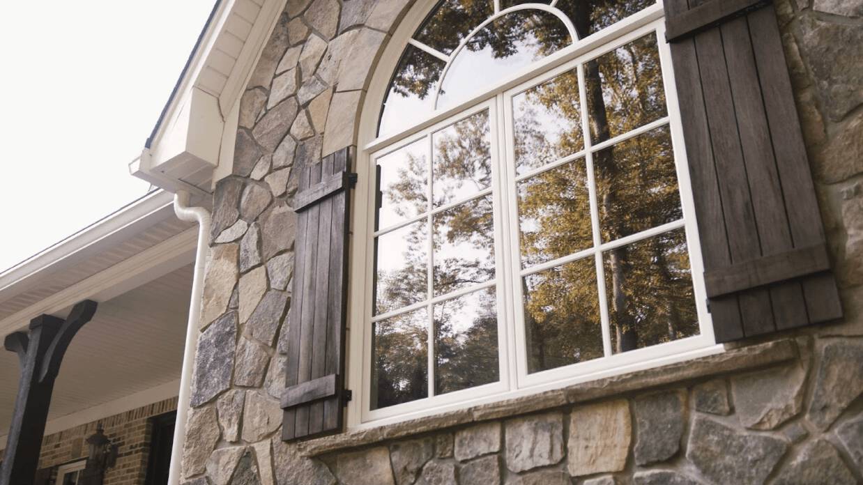 Modern home featuring black fiberglass windows and manufactured stone siding.