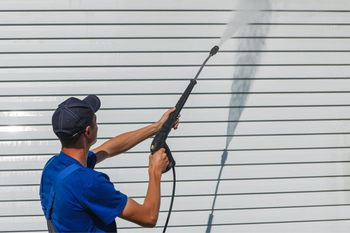 Man power washing white siding