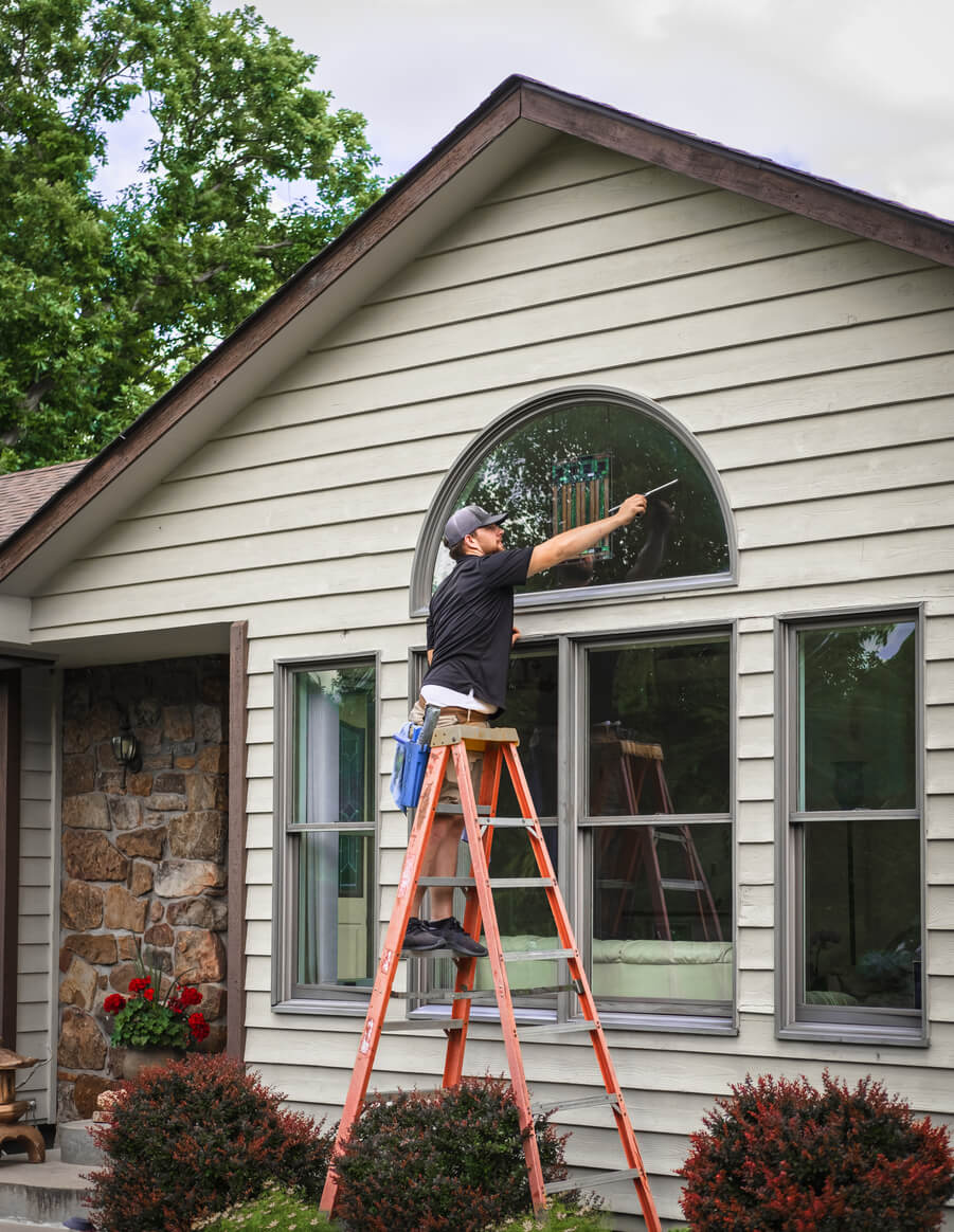 Man standing on a ladder and cleaning windows.