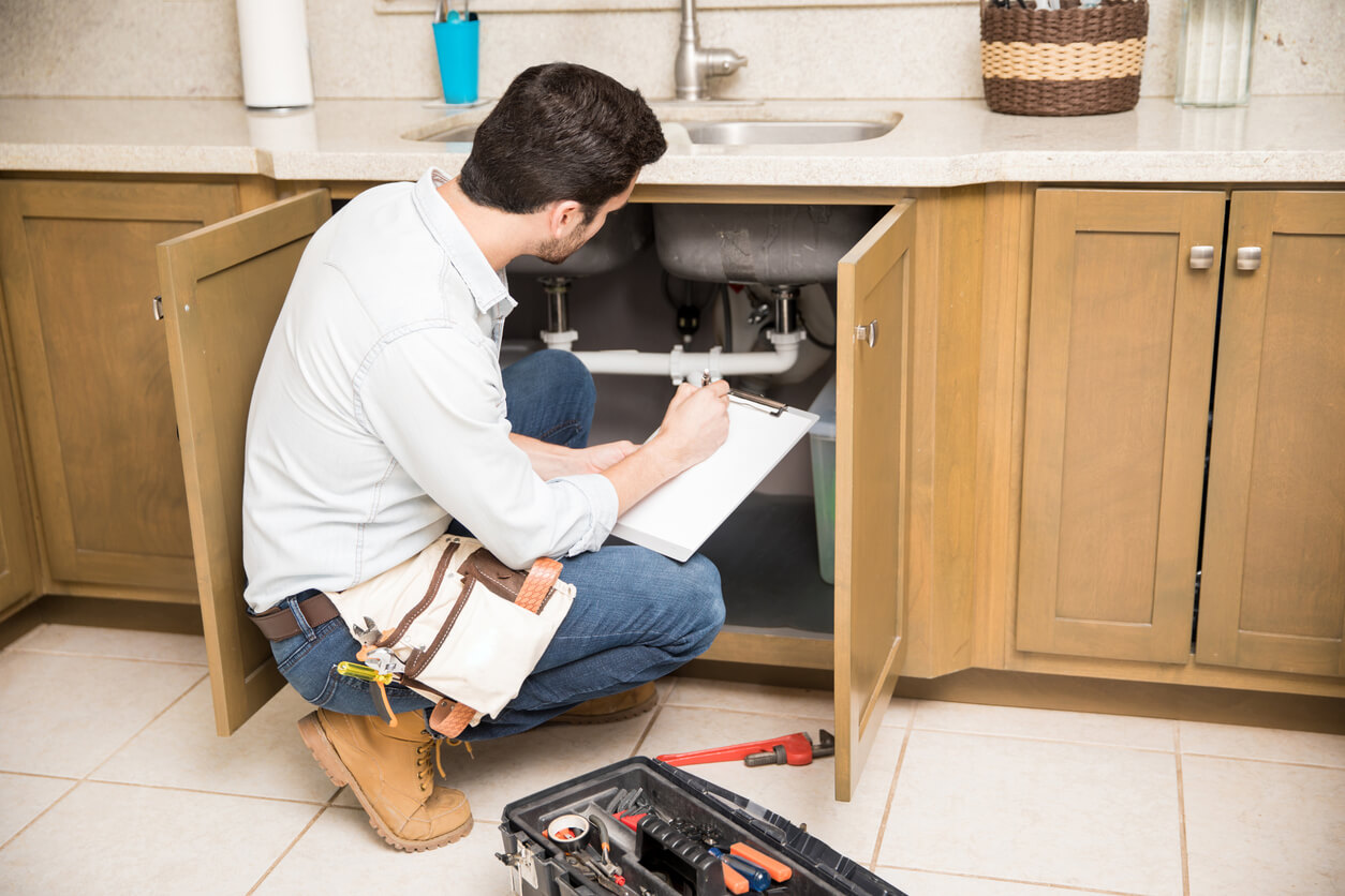 plumber inspecting piping underneath kitchen sink