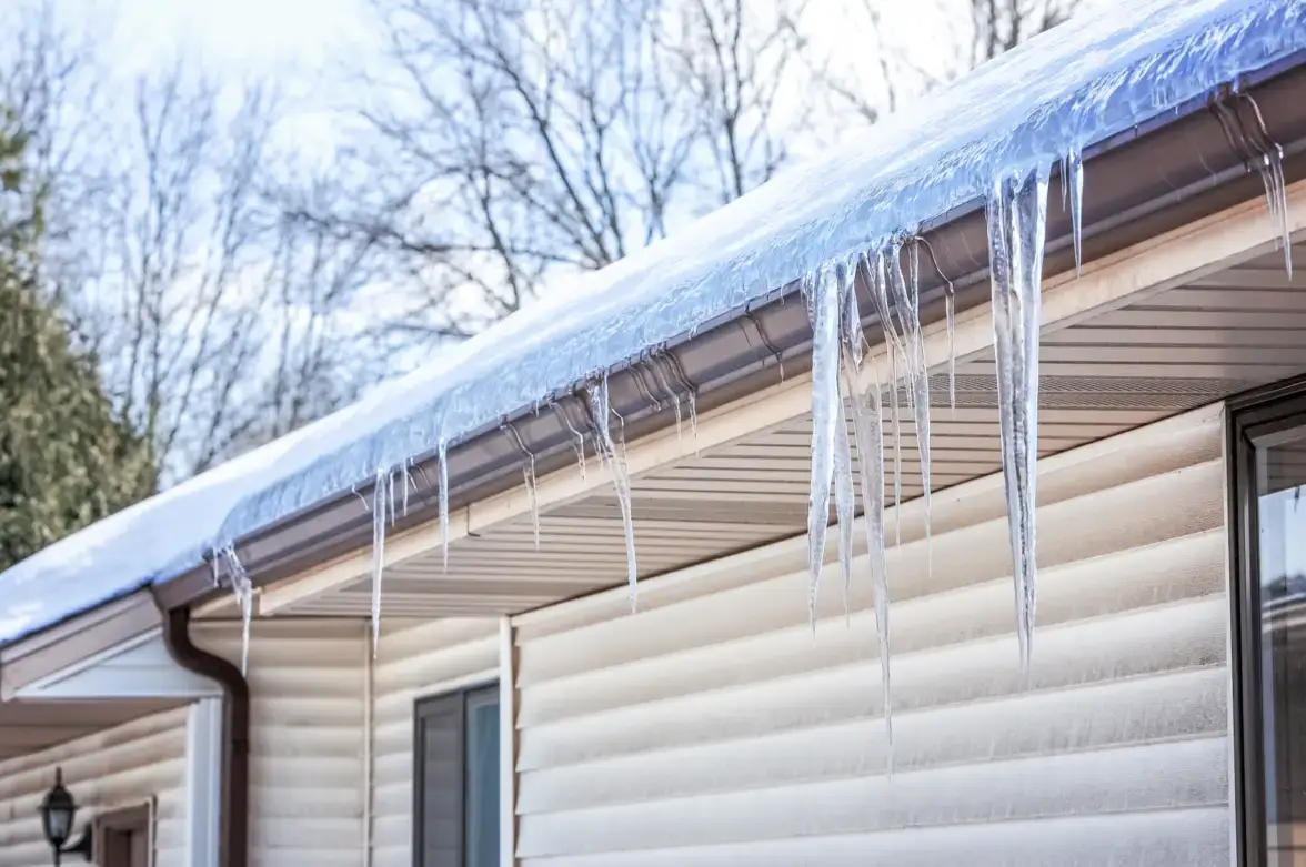 Icy buildup forming an ice dam on home gutters after a winter storm.