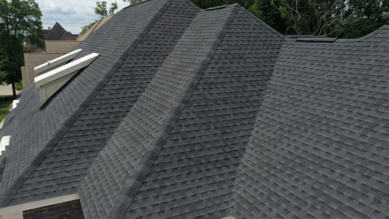 A dark gray asphalt roof with gables and dormers, highlighting durable types of shingles.